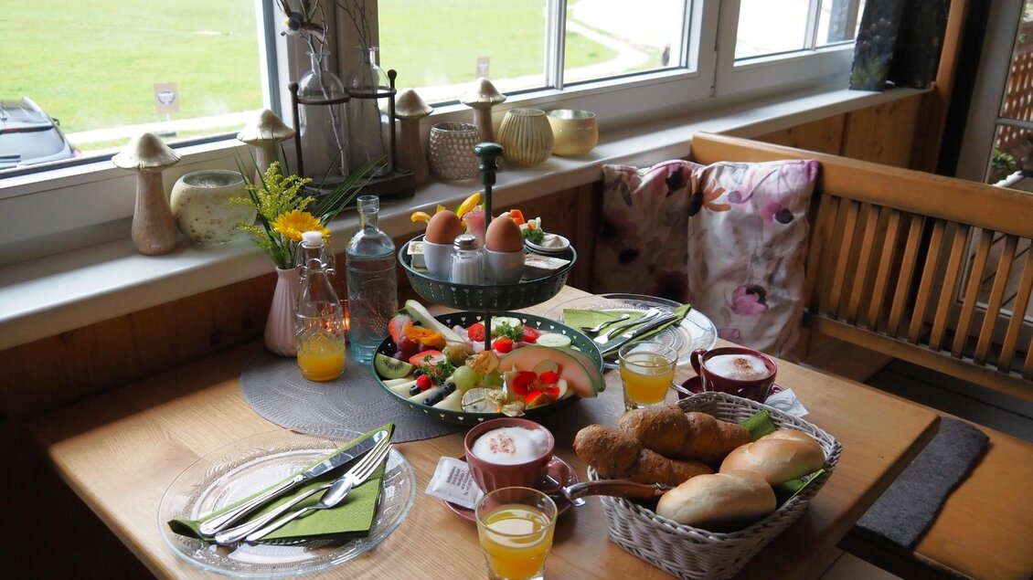 Ein gedeckter Tisch mit einer Vielzahl von Frühstücksdelikatessen, darunter frisches Obst, Brötchen und Eier. Dazu gibt es Säfte und eine gemütliche Atmosphäre mit Tageslicht. | © TVB Ausseerland Salzkammergut