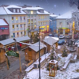 A picturesque Christmas market in a town with snow-covered stalls. The surroundings are festively lit, and there is snow on the roofs. | © Stadtgemeinde Friedberg
