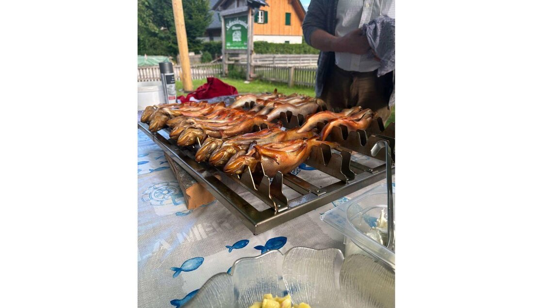 Gegrillte Fische auf einem Rost, bereit zum Servieren. Im Vordergrund befindet sich eine Schüssel mit einer Beilage. | © Kainzinger