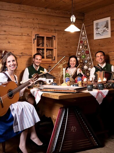 Eine Gruppe von fünf Musikern sitzt in einem rustikalen Raum und spielt traditionelle Instrumente. Sie tragen traditionelle Kleidung und genießen die gesellige Atmosphäre. | © Emmanuel Feiner