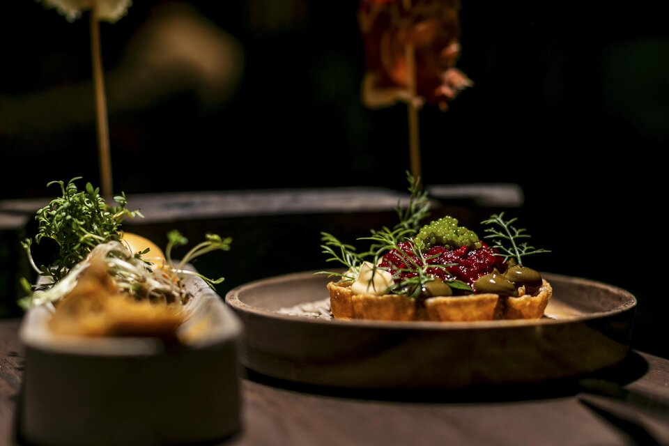 Ein elegantes Gericht auf einem Teller, dekoriert mit frischen Kräutern und einer bunten Garnitur. Im Hintergrund sind weitere appetitliche Speisen zu sehen. | © jamst_winzertisch 220324_42
