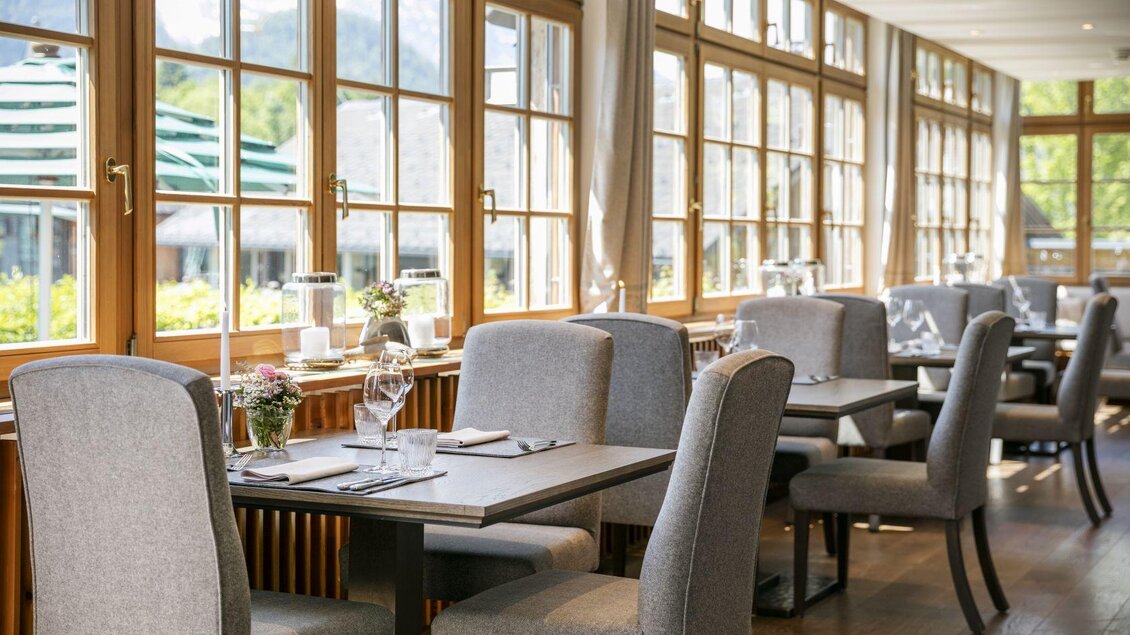 Ein modernes Restaurant mit großen Fenstern und viel natürlichem Licht. Die Tische sind elegant gedeckt und laden zum Verweilen ein. | © Seehotel Grundlsee