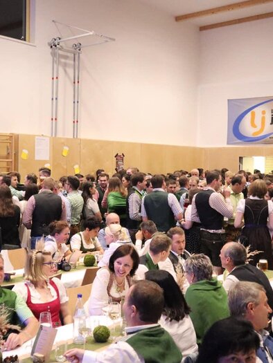 A lively event with many people in traditional attire. There are festively decorated tables and a cheerful atmosphere. | © Gemeinde Gasen