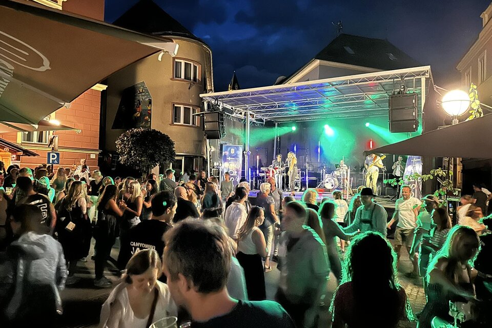 Eine lebhafte Veranstaltung bei Nacht mit vielen Menschen, die tanzen und Spaß haben. Auf der Bühne spielt eine Band mit bunten Lichtern. | © Thomas Rauninger