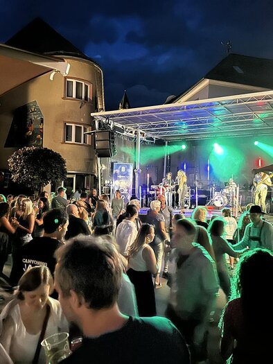 A lively event at night with many people dancing and having fun. On stage, a band is playing with colorful lights. | © Thomas Rauninger