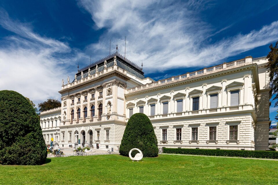 Ein historisches Gebäude mit elegantem Architekturstil und schönen grünen Gartenanlagen. Der Himmel ist blau mit einigen Wolken. | © Graz Tourismus - Harry Schiffer
