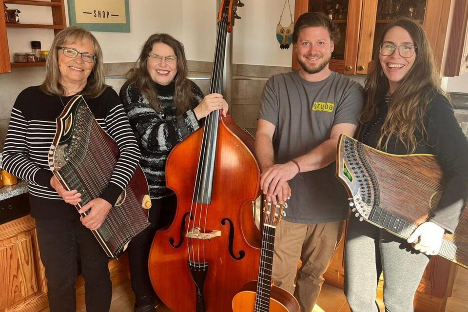 Die vier Musikanten der Gruppe Saitenspiel, drei Frauen und ein Mann, stehen mit ihren Instrumenten vor der gemütlichen Küche des Simalhofes. | © Gabriele Marchner Trieb
