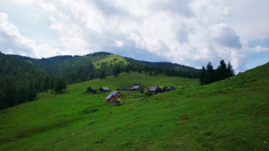 Eine malerische Landschaft mit sanften Hügeln und einem kleinen Dorf im Grünen. Der Himmel ist bewölkt, und die Umgebung ist von Bäumen umgeben. | © Michael Geißler
