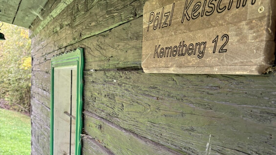 Verwitterte Holzwand eines alten Hauses mit grün gerahmtem Fenster und der Holztafel „Pölzl Keischn, Kemetberg 12“ | © Kohlbacher