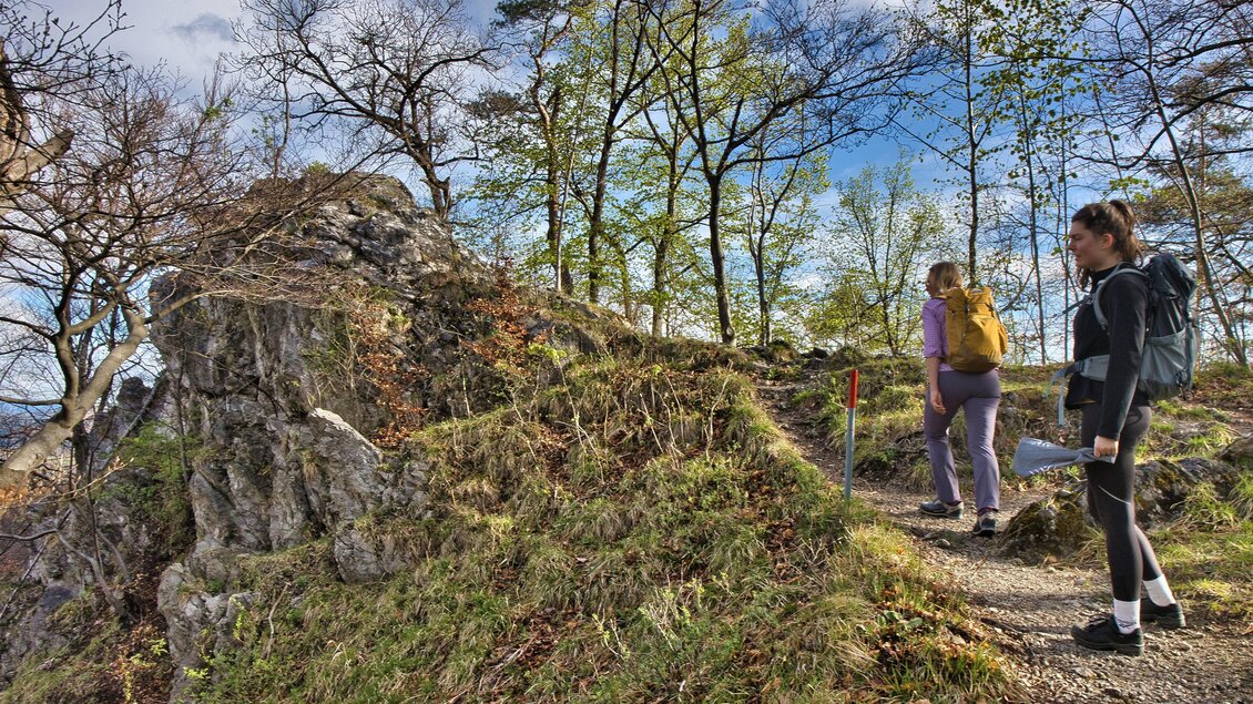 Zwei Wanderinnen mit Rucksäcken gehen auf einem schmalen, felsigen Waldweg über eine Anhöhe zwischen Gösting und Thal. | © Weges