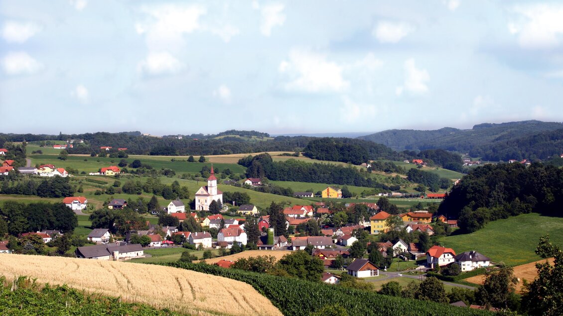 Ein malerisches Dorf umgeben von sanften Hügeln und Weinbergen. Der Himmel ist klar und die Landschaft ist grün und einladend. | © Gemeinde Unterlamm