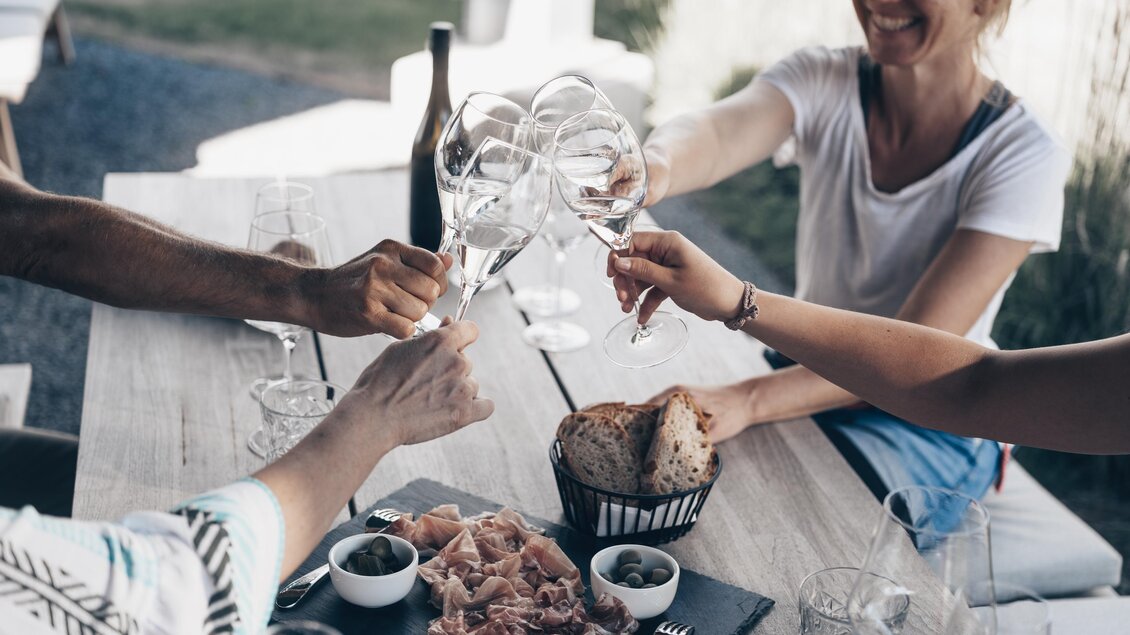 Eine Gruppe von Freunden, die Gläser anstoßen. Auf dem Tisch liegen Snacks und Getränke. | © Ian Ehm