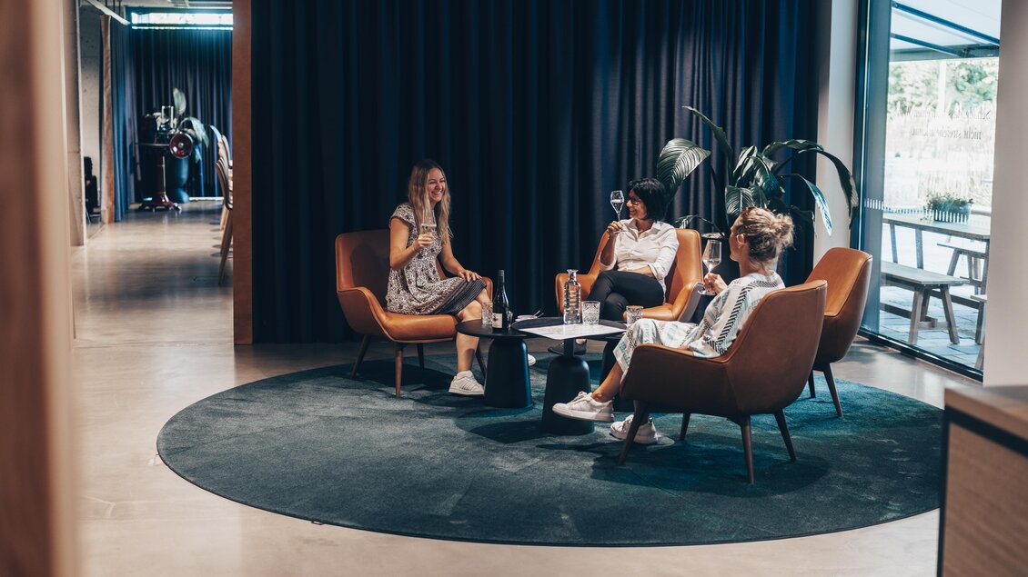 Drei Frauen sitzen in modernen Sesseln und unterhalten sich an einem Tisch. Der Raum ist hell und freundlich gestaltet. | © Ian Ehm