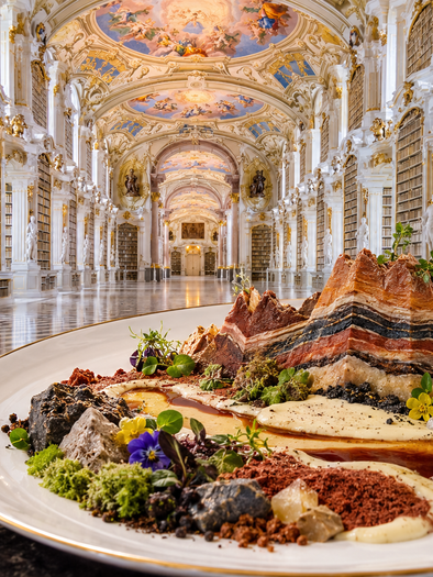 An artfully arranged dish on an elegant plate, showcasing a mountainous structure made from various ingredients. In the background, there is an impressive library with tall shelves and magnificent ceilings.