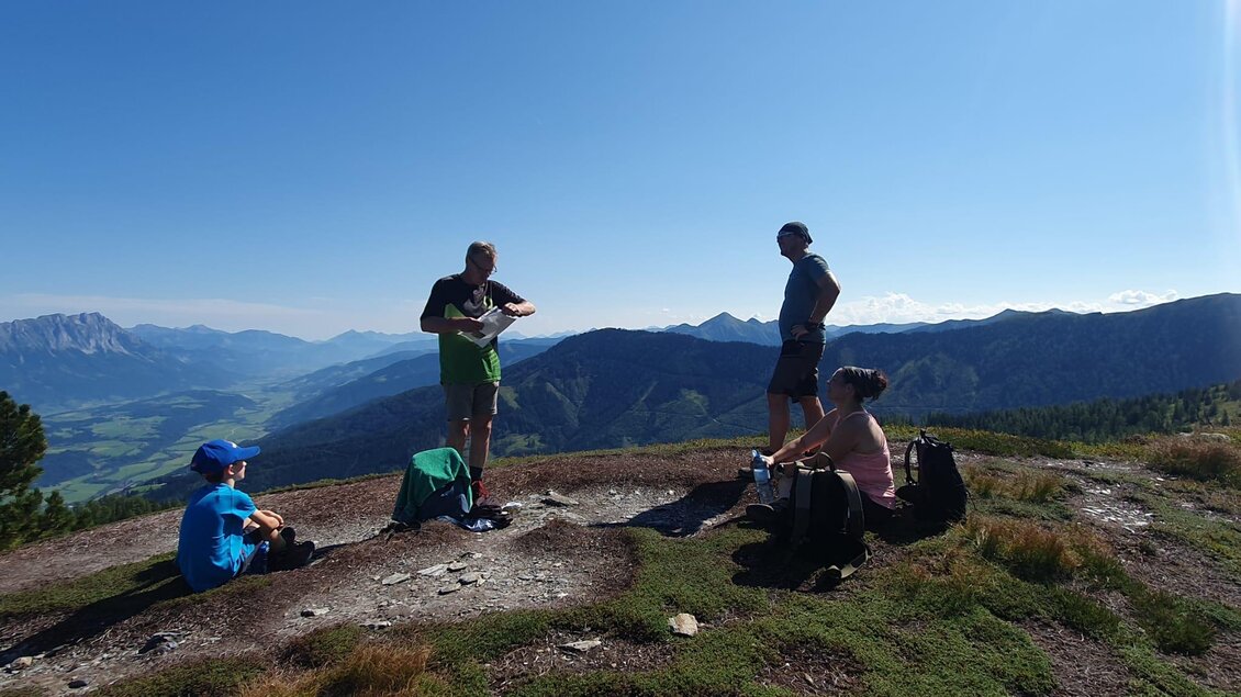 Eine Gruppe von vier Personen auf einem Berg. Im Hintergrund sind die Alpen und ein blauer Himmel zu sehen. | © Hubert Pleninger