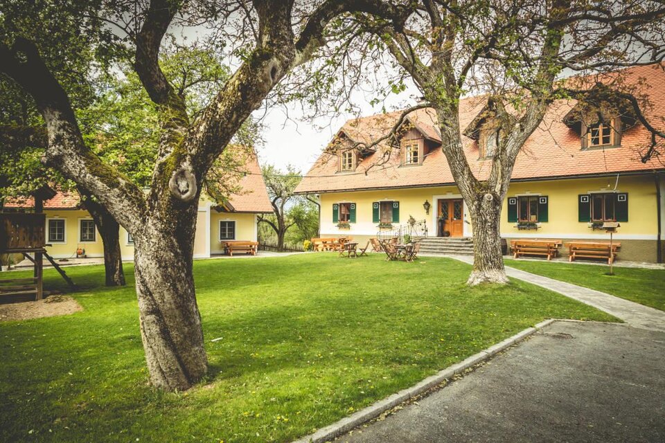 Ein charmantes Bauernhaus mit einem gepflegten Garten und alten Bäumen. Es gibt Sitzgelegenheiten im Freien und eine ruhige, entspannte Atmosphäre. | © Familie Krottmayer