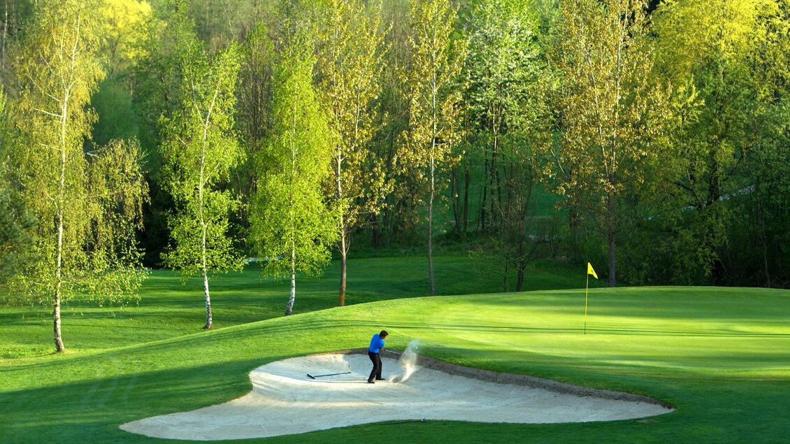 Golfer schlägt Ball aus Sandbunker auf Golfplatz in Maria Lankowitz, umgeben von Bäumen und Grünflächen.  | © GEPA Pictures