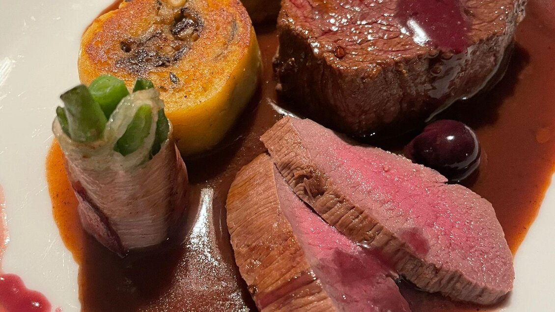 Ein delikates Gericht aus zartem Fleisch, serviert mit einer Rotweinsauce und verschiedenen Beilagen. Die Präsentation zeigt frisches Gemüse und eine ansprechende Farbkombination. | © Winterleitenhütte