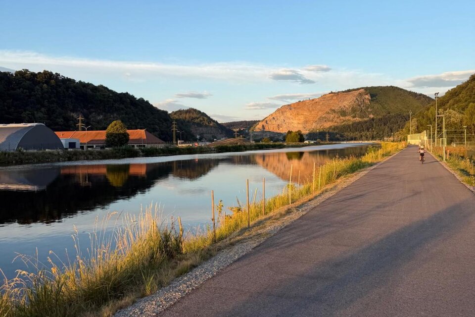 Radweg entlang der Mur mit bewaldeten Hängen und Berg im Hintergrund. | © Team Grat²Event