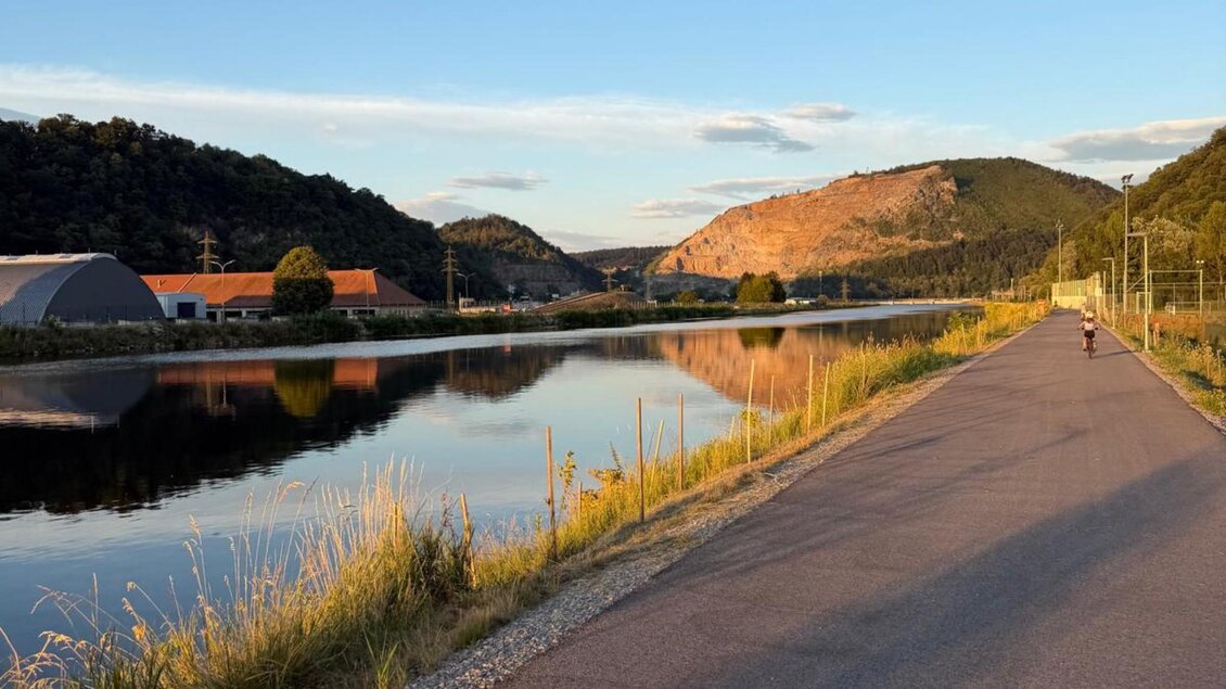 Radweg entlang der Mur mit bewaldeten Hängen und Berg im Hintergrund. | © Team Grat²Event