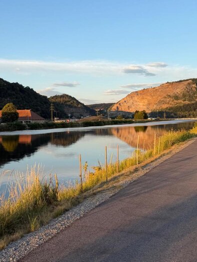 Radweg entlang der Mur mit bewaldeten Hängen und Berg im Hintergrund. | © Team Grat²Event