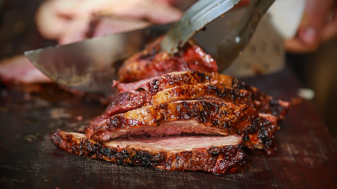 Saftig geschnittenes Fleisch auf einem Schneidebrett. Die goldbraune Kruste und der rauchige Duft verleihen dem Gericht besonderen Geschmack. | © obeStock_349753698 (c) Eduardo