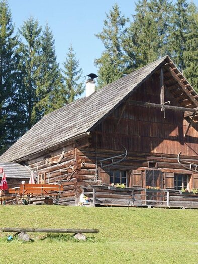 <p>Die Eselalm in Bad Mitterndorf mit einer Holzverkleidung und Sitzmöglichkeiten mit Sonnenschirmen im Freien ist umgeben von der grünen Landschaft des Ausseerlandes.</p> | © Eselalm, Bad Mitterndorf