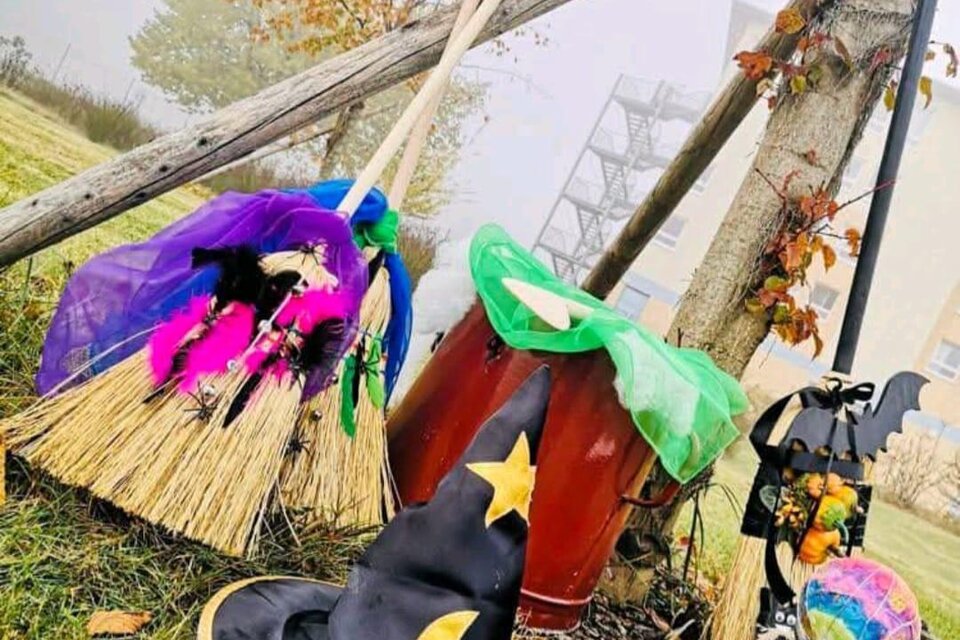 Eine Halloween-Dekoration mit einem Hexenhut, einem Besen und bunten Accessoires. Im Hintergrund sind herbstliche Bäume und eine unklare Szenerie zu sehen. | © H2O-Hoteltherme GmbH