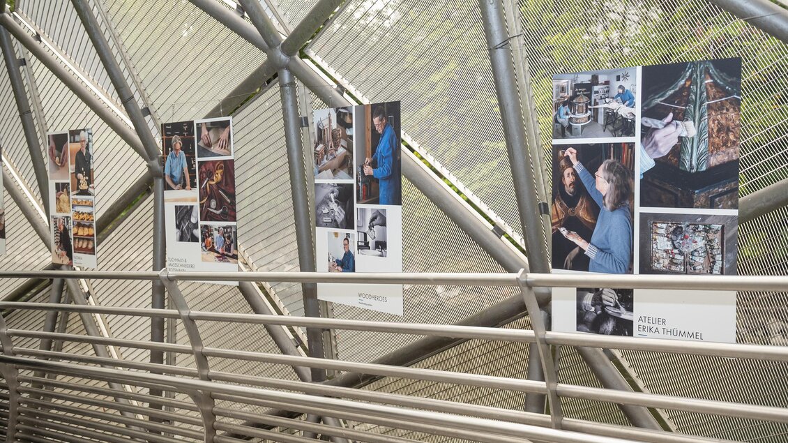 Bildtafeln der Ausstellung „Handwerk als Kulturgut“ sind entlang des Metallstegs der Murinsel in Graz angebracht. | © Bernd Grosseck