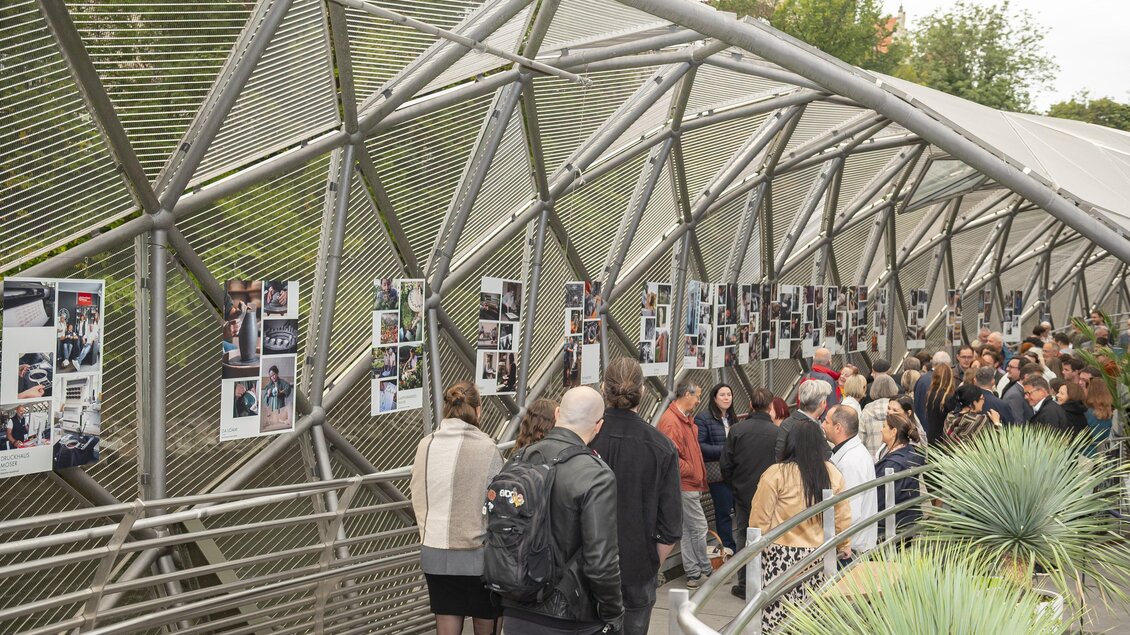 Besucher gehen durch die Ausstellung „Handwerk als Kulturgut“ mit Bildtafeln auf der Murinsel in Graz. | © Bernd Grosseck