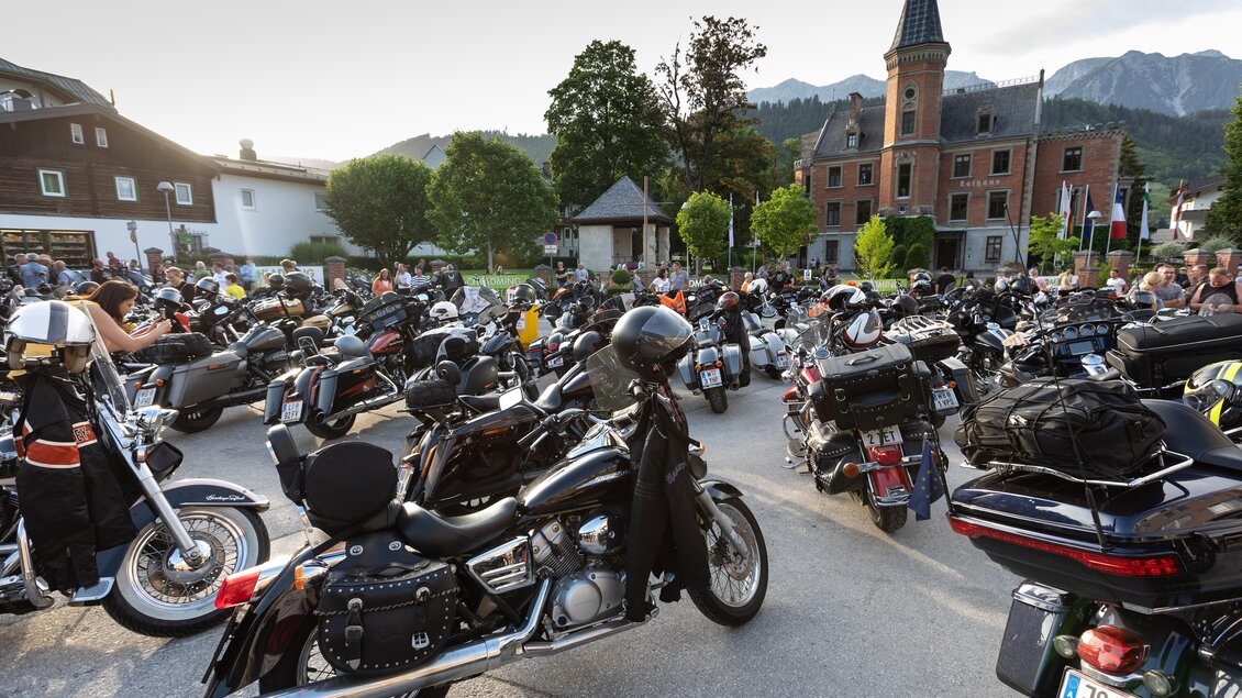 Eine große Ansammlung von Motorrädern in einer malerischen Umgebung. Im Hintergrund ist ein historisches Gebäude und Berge zu sehen. | © Harald Steiner