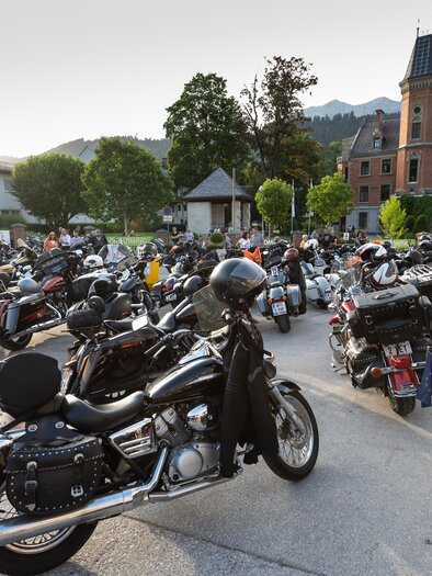 Eine große Ansammlung von Motorrädern in einer malerischen Umgebung. Im Hintergrund ist ein historisches Gebäude und Berge zu sehen. | © Harald Steiner