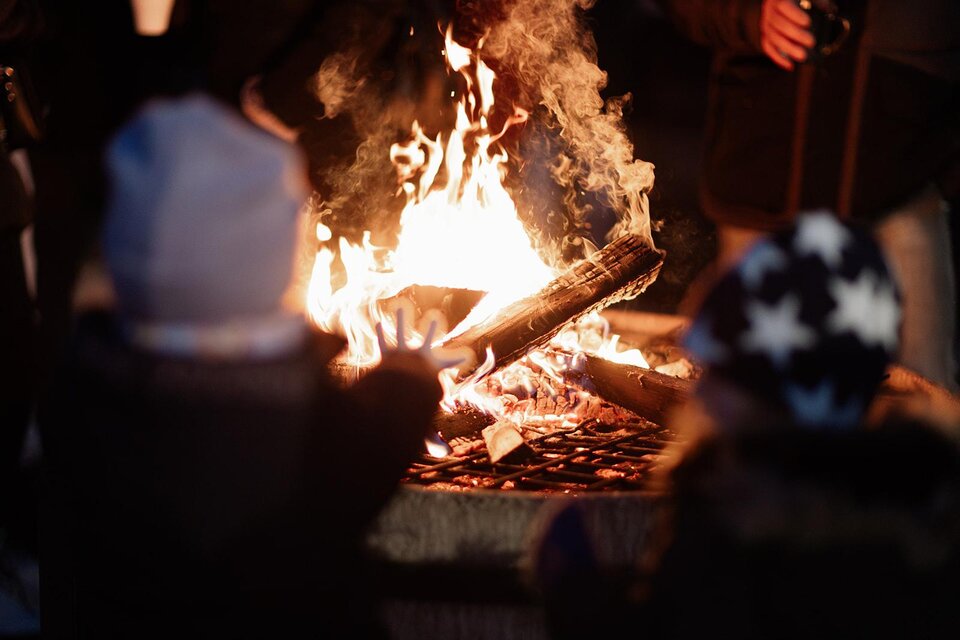 Ein Lagerfeuer mit flammenden Holzscheiten. Im Vordergrund sind zwei Kinder zu sehen, die das Feuer beobachten. | © © TVB Südsteiermark – Achromatic Photography (32)