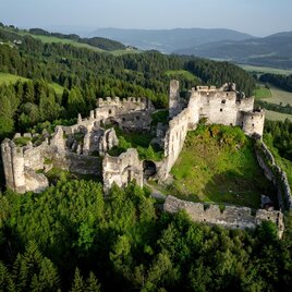 Eine alte Ruine, umgeben von dichten Wäldern und sanften Hügeln. Die Burg liegt malerisch in der Landschaft. | © Tv Murau