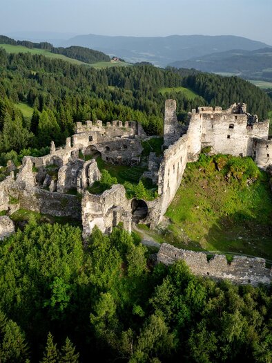 An old ruin, surrounded by dense forests and gentle hills. The castle is situated picturesque in the landscape. | © Tv Murau