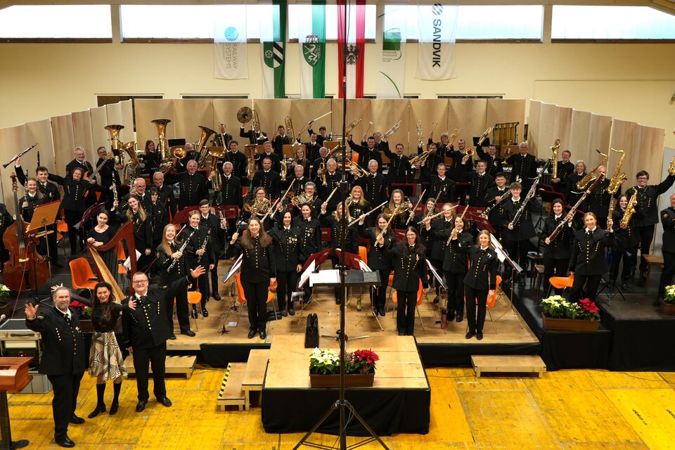 Ein großes Orchester auf der Bühne, das aus vielen Musikerinnen und Musikern besteht. Die Atmosphäre ist festlich und die Musiker zeigen ihre Begeisterung. | © Peter Haslebner