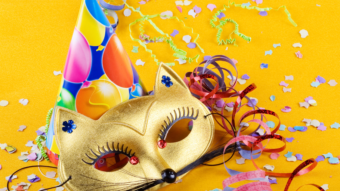 Eine elegante, goldene Faschingsmaske mit Schnurrhaaren und Katzenohren, und ein Partyhut mit Luftballons, bunten Luftschlangen und Konfetti machen Lust auf die Feierlichkeiten rund um den Ausseer Fasching in der fünften Jahreszeit. | © Canva