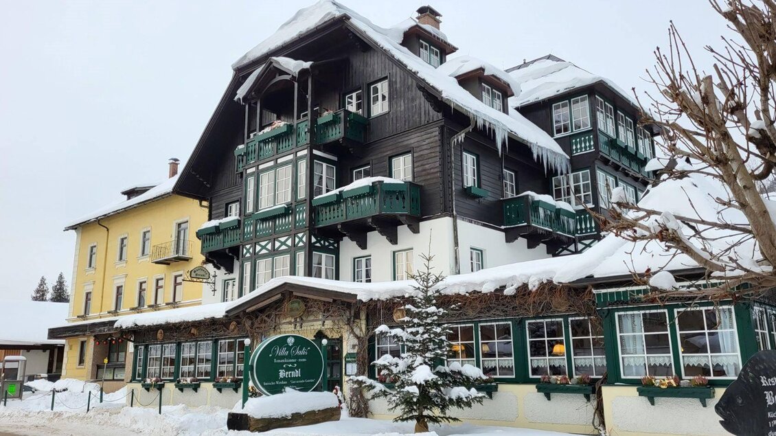 Das charmante VILLA SALIS - Restaurant Berndl in der winterlichen Landschaft von Altaussee mit viel Schnee. Die Fassade ist traditionell mit viel Holz und grünen Balkonen, und mit viel Liebe zum Detail gestaltet. Die Balkone und Fenster ermöglichen einen Blick auf die traumhafte Umgebung. | © Petra Kirchschlager