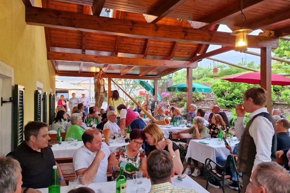 Ein geselliges Beisammensein unter warmem Holzdach – Stimmen, Lachen und der Duft regionaler Köstlichkeiten verschmelzen zu einem echten Wohlfühlmoment. Hier beim Buschenschank Matzhold in Fehring wird Gemeinschaft gelebt, Zeit geteilt und Genuss ganz selbstverständlich zelebriert. Ein Ort, an dem man bleibt, weil es sich einfach gut anfühlt. | © Buschenschank Matzhold