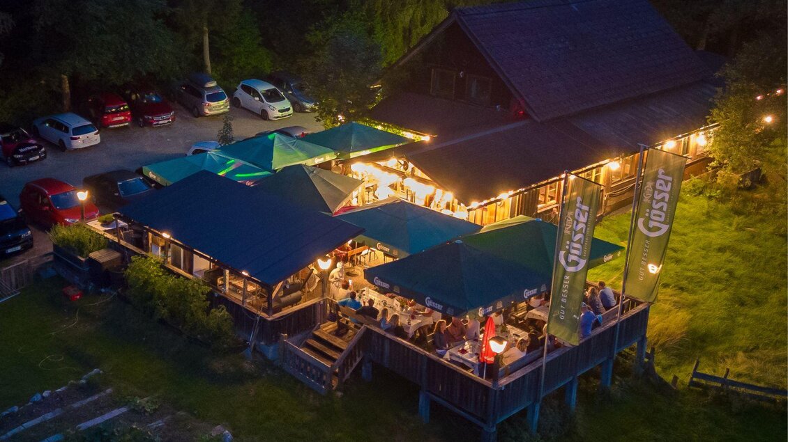 Die Hubertushütte am Abend. Die Lichterketten leuchten und unter den Schirmen sitzen die Gäste und genießen die Amtosphäre | © Zechmann