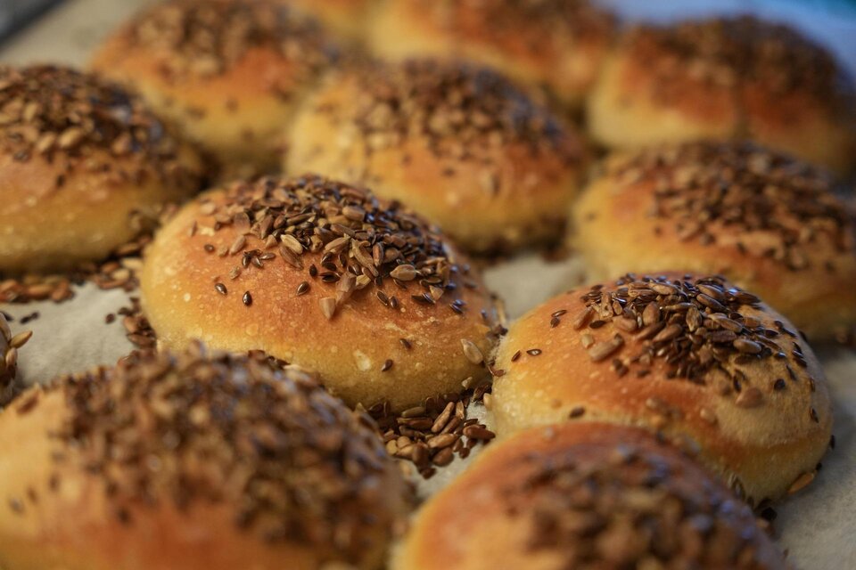 Frisch gebackene Brötchen mit einer goldbraunen Kruste und Leinsamen obendrauf. Die Brötchen liegen auf einem Backblech. | © Pixabay
