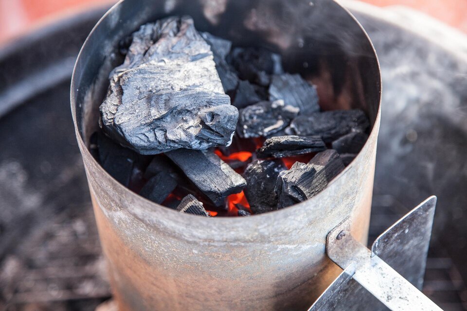 Ein Grillanzünder mit glühenden Holzkohlebriketts. Der Rauch steigt nach oben und zeigt, dass die Kohlen bereit zum Grillen sind. | © Pixabay