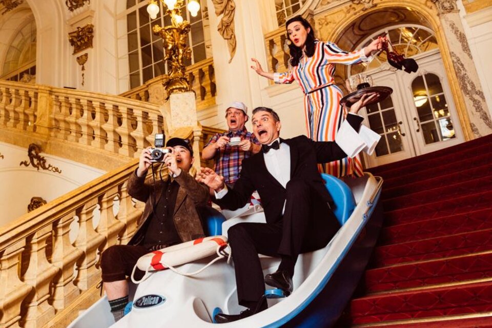 Eine Gruppe von Menschen fährt in einem Boot die Treppe hinunter und hat Spaß. Sie sind in eleganter Kleidung und machen Fotos. | © Ingo Pertramer