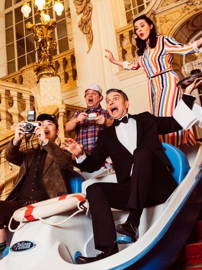 Eine Gruppe von Menschen fährt in einem Boot die Treppe hinunter und hat Spaß. Sie sind in eleganter Kleidung und machen Fotos. | © Ingo Pertramer