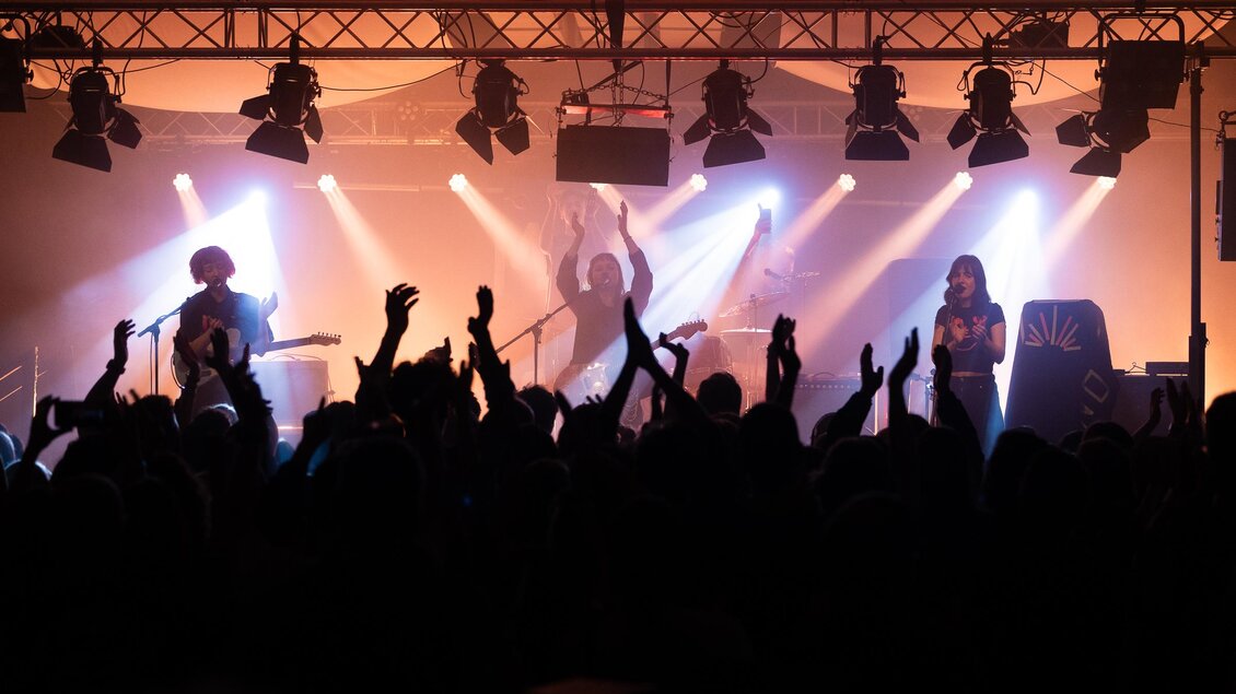 Musikband auf der Bühne mit Publikum im Vordergrund | © Michael Fasching