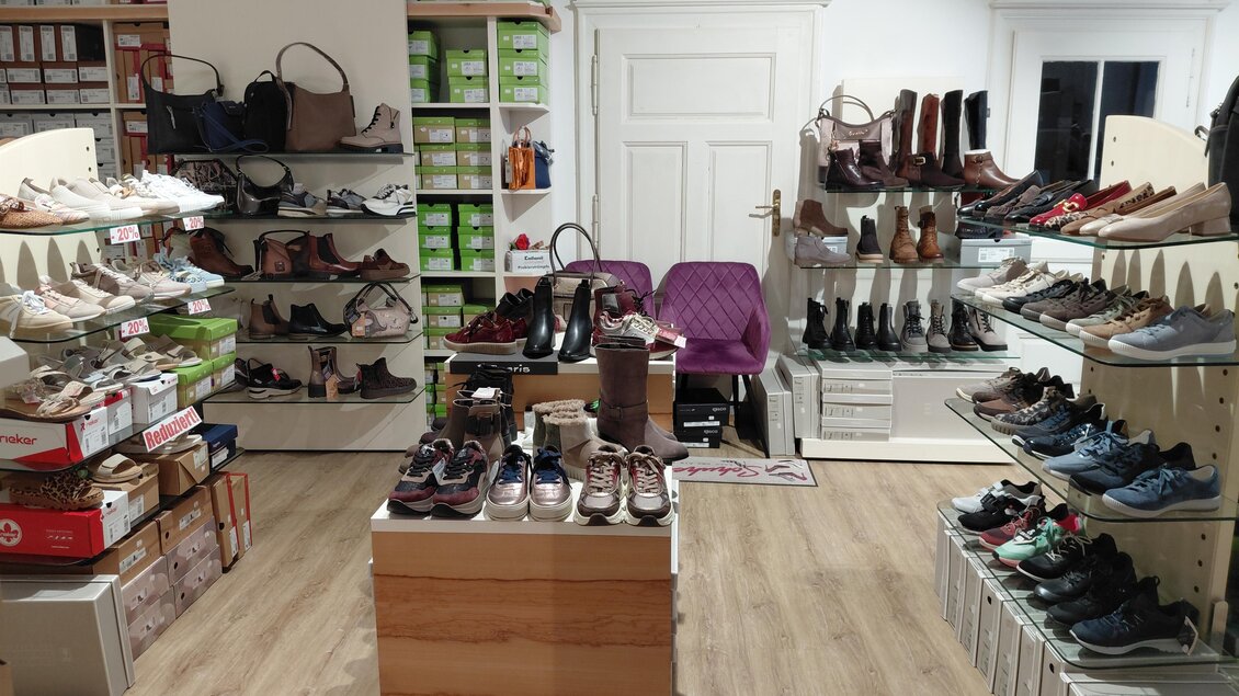 Ein Schuhgeschäft mit verschiedenen Regalen voller Schuhe und Stiefel. In der Mitte steht ein Verkaufstresen und die Wände sind mit Taschen dekoriert. | © Gerald Gollmann