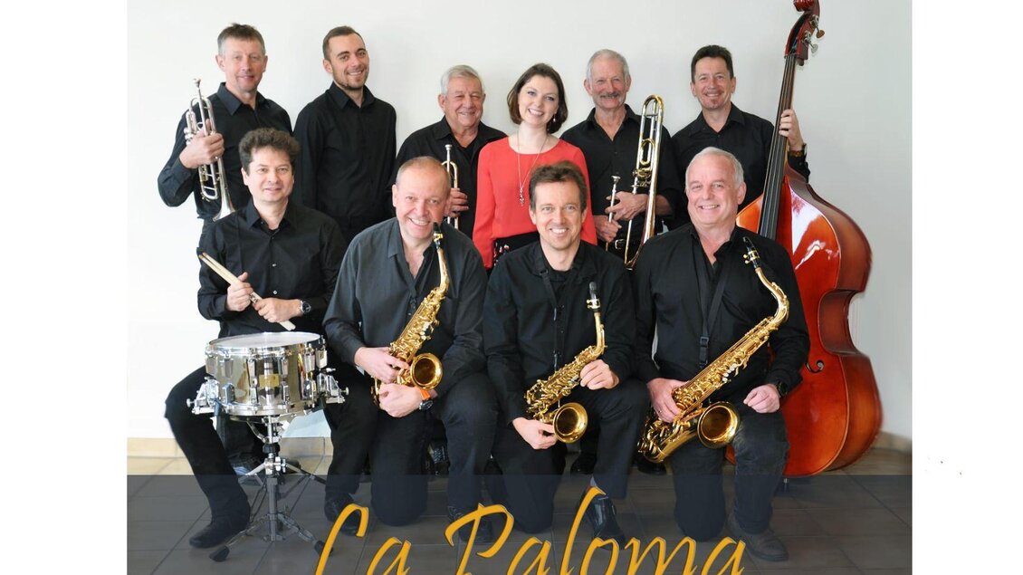 Die Bandmitglieder, bestehend aus Ärzten, die sich zur Musikgruppe "La Paloma" aufgestellt haben. Sie halten ihre verschiedenen Musikinstrumente, wie zum Beispiel Saxophon, Posaune und Trompete, in den Händen.  | © JazzMed