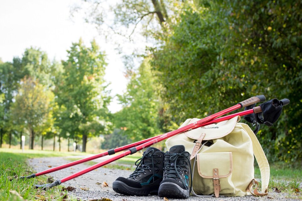 Ein Paar Wanderschuhe und ein Rucksack liegen auf einem Weg. Neben den Schuhen stehen zwei Wanderstöcke. | © Kurkommission Bad Blumau