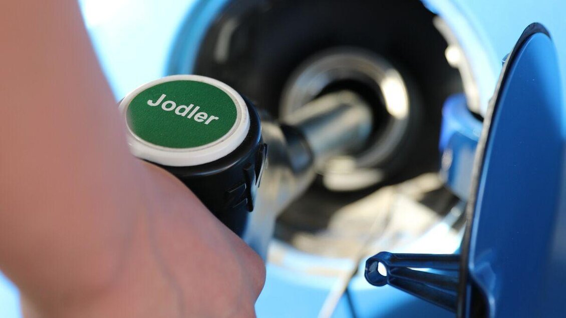 Eine Person tankt Benzin in ein Auto. Die Zapfpistole zeigt die Aufschrift "Jodler". | © Steirisches Volksliedwerk