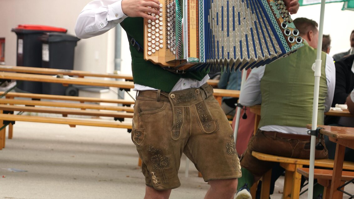 Zu sehen ist ein Musiker mit Harmonika am Kirchplatz. | © Franz Kern